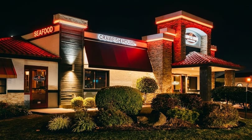 Exterior of Crawfish House restaurant at night, with red neon signs and illuminated landscaping.